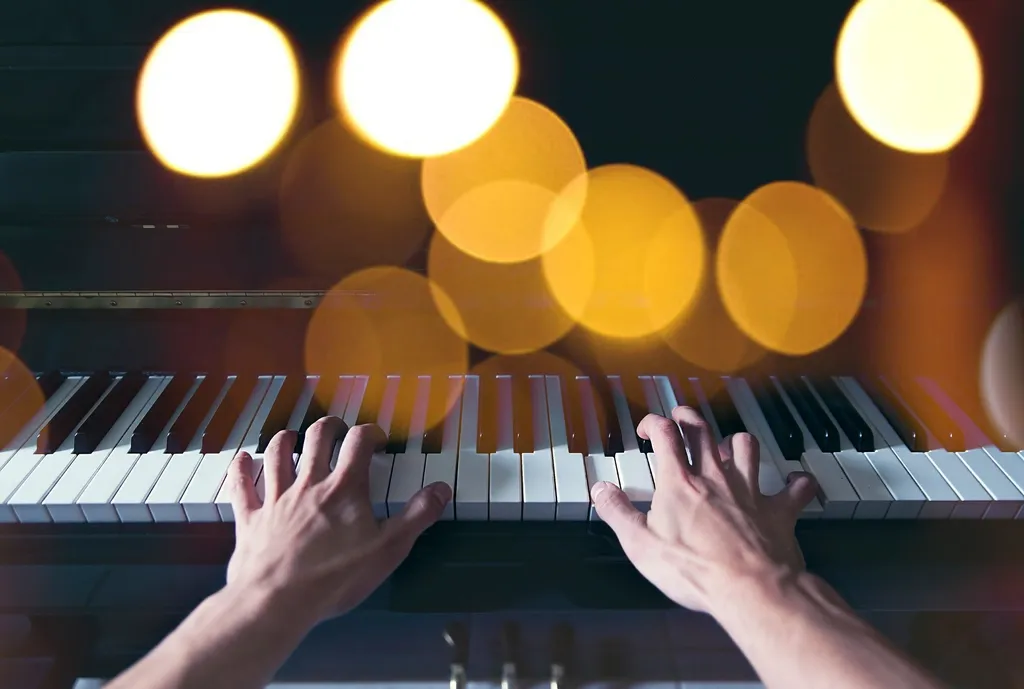 Hands playing piano keys under warm lights